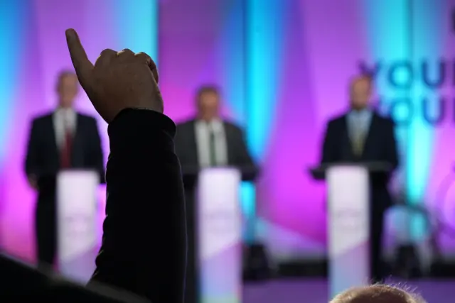 An arm in the air asking a question at the debate