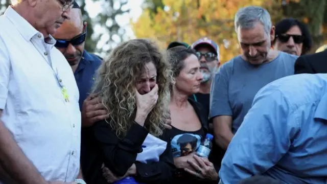 A woman cries and is comforted by another woman, next to her is a man in a grey t-shirt who is Michael