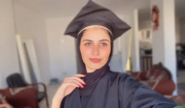 Woman in black hijab, gown and graduation cap