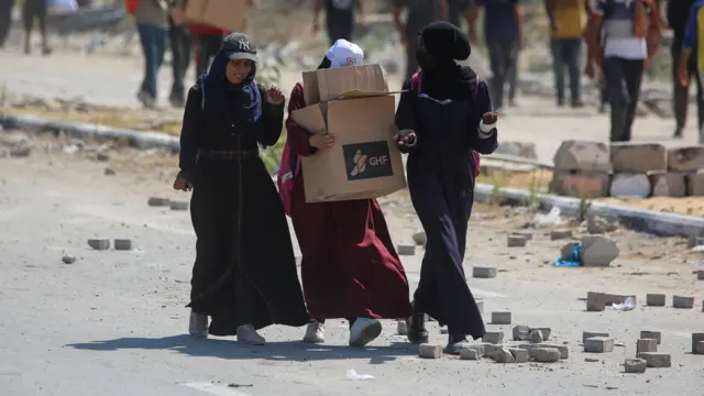 Women carry GHF boxes