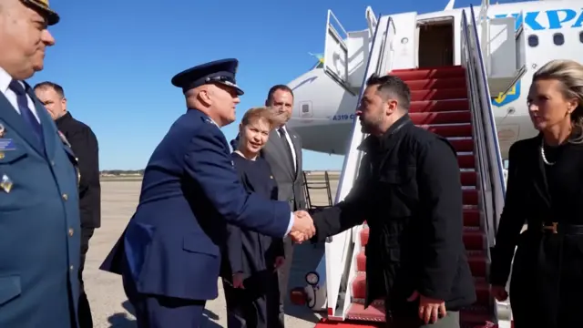 Zelensky shakes hands after departing his plane with a military official