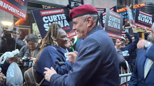 Curtis Sliwa, in a blue jacket and his signature red beret, greets his supporters