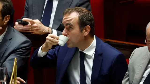 Lecornu drinking from a small coffee cup in the National Asembly