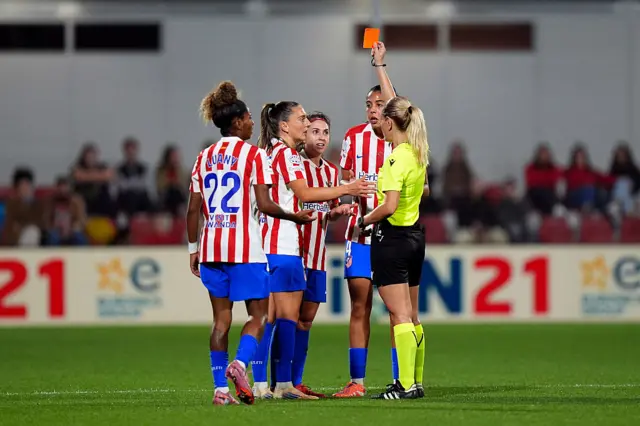 Eleni Antoniou shows a red card to Alexia Fernández of Atletico de Madrid