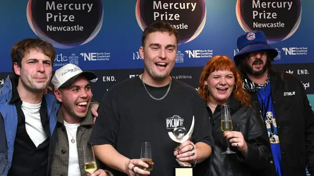 Sam Fender celebrates with a glass of wine and his award after winning the Mercury Prize 2025 in Newcastle