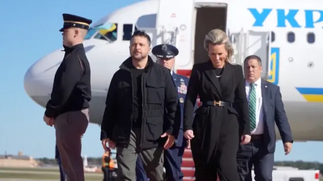 Zelensky seen walking off the plane with a woman as military officials look on
