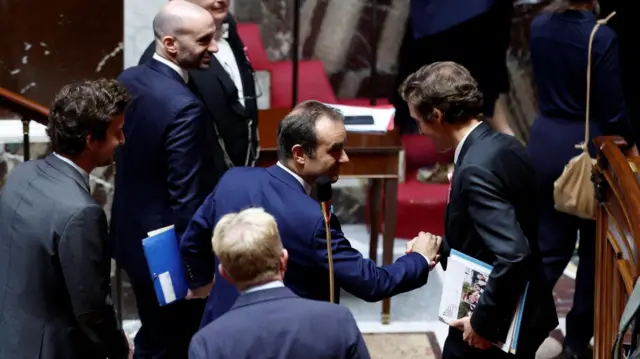 Sebastien Lecornu shakes hands with Education Minister Edouard Geffray after the result on the second no-confidence motion
