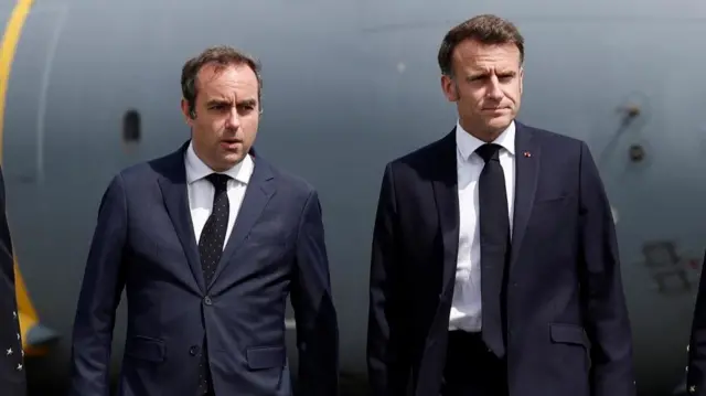 Sebastien Lecornu and Emmanuel Macron stand next to each other while wearing dark suits.