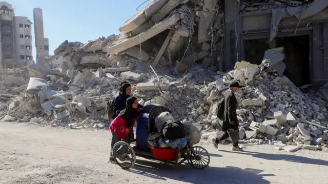 Family in Gaza with rubble in background