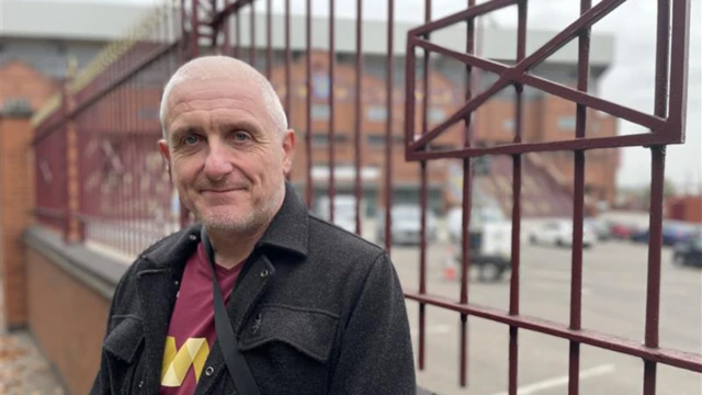 David Moss stands in front of a fence
