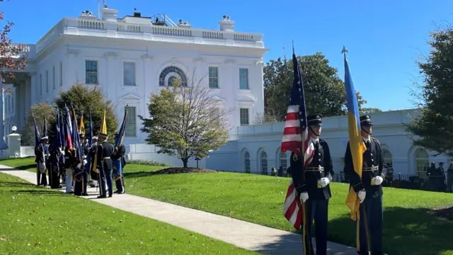 honour guard soldiers holding US and Ukraine flags