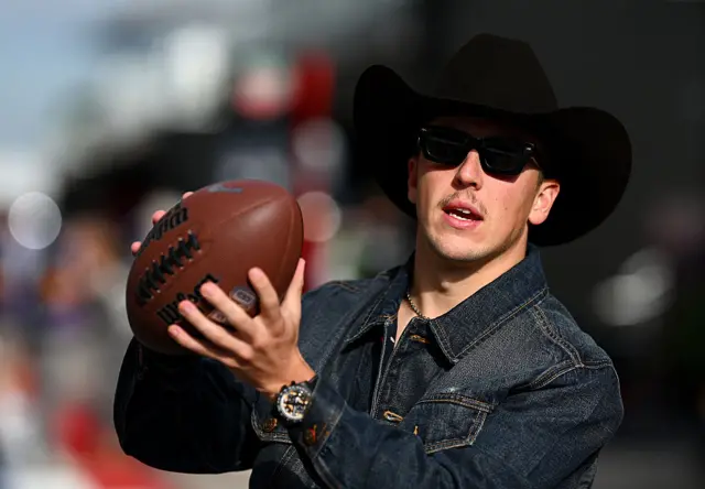 Liam Lawson wears a cowboy hat while holding an American football