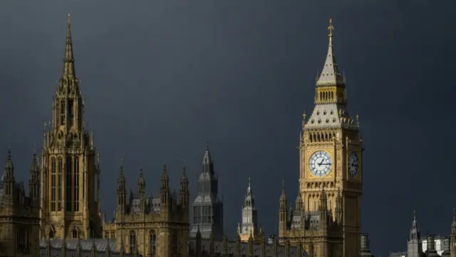 A view of the top of the Houses of Parliament in central London on a cloudy day.