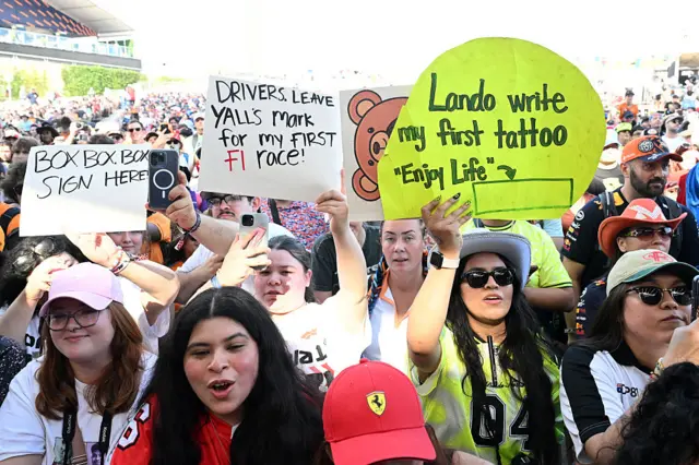 Fans hold up signs for drivers in the fan zone at the United States Grand Prix