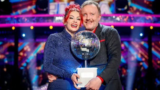 Dianne Buswell and Chris McCausland holding the Glitterball trophy