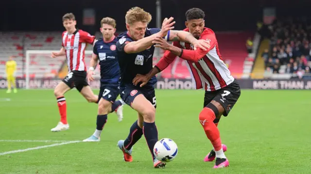 Reeco Hackett of Lincoln City battles with Carl Piergianni of Stevenage