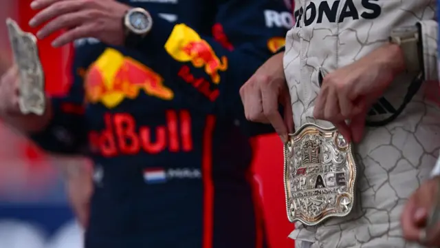 Max Verstappen and George Russell wearing their belt buckle medals
