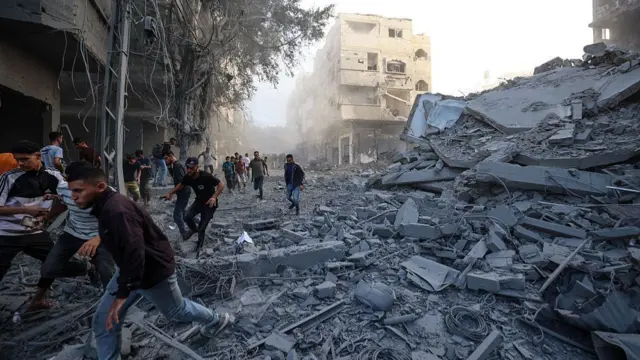 People run for cover following an Israeli strike that targeted a building in the Bureij camp for Palestinian refugees in the central Gaza Strip on October 19, 2025.