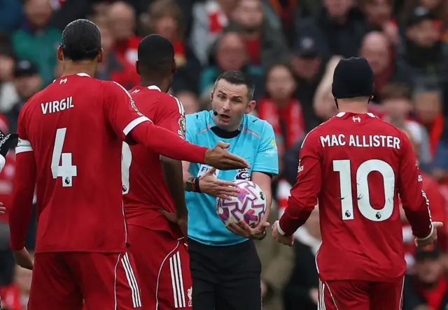 Liverpool players surround Oliver after a call against them