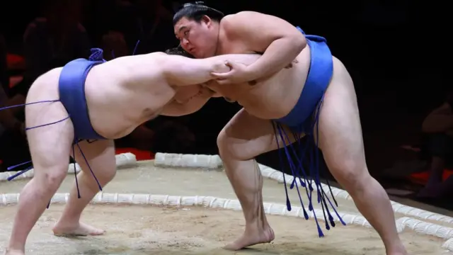 Two sumo wrestlers (Aonishki and Onasato) grapple during a sumo bout