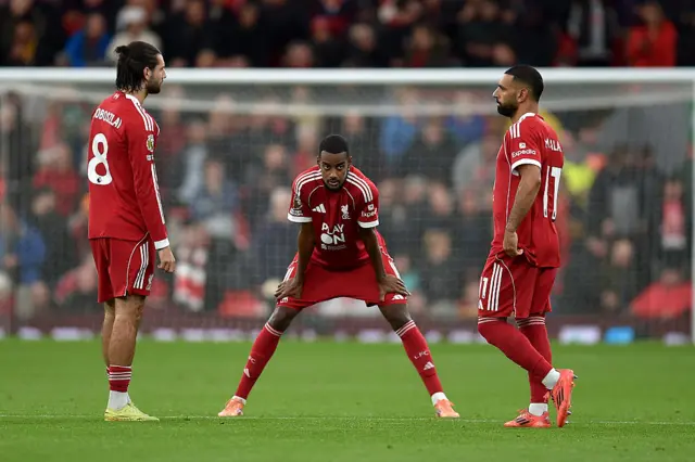 Isak, Szobozslai and Salah stand on the pitch ahead of the second half