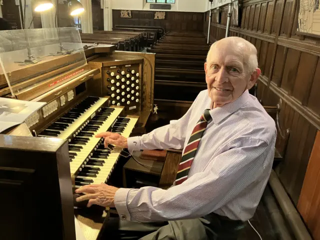 An elderly man playing a church organ