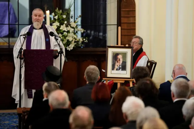 A vicar speaking at a funeral service