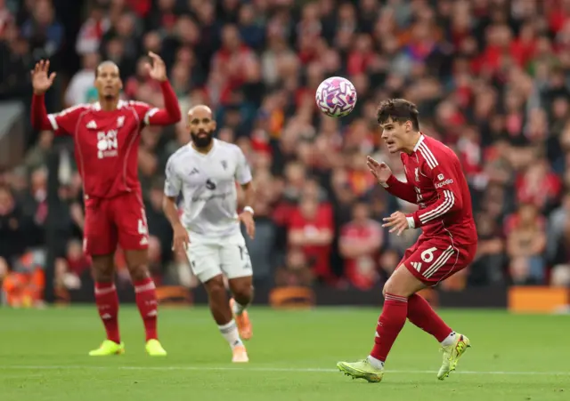 Van Dijk waves his arms in the background as Kerkez looks to give the ball away