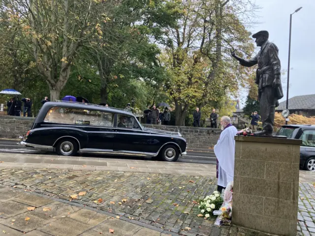 The hearse passes a statue of Dickie Bird