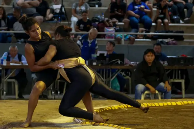 Two girls wrestling in a sumo ring