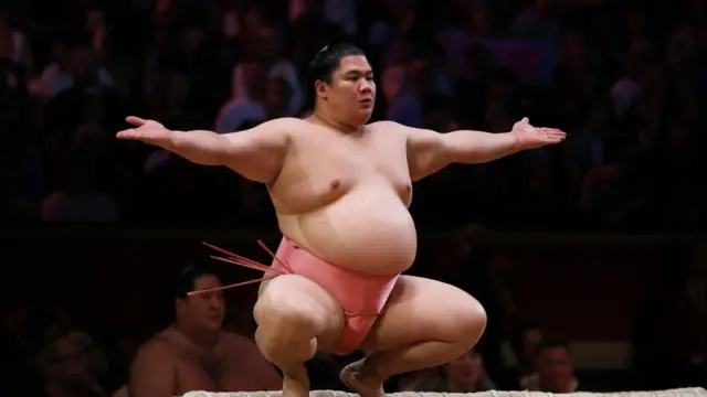 Ura in a squat with his arm wide before a bout