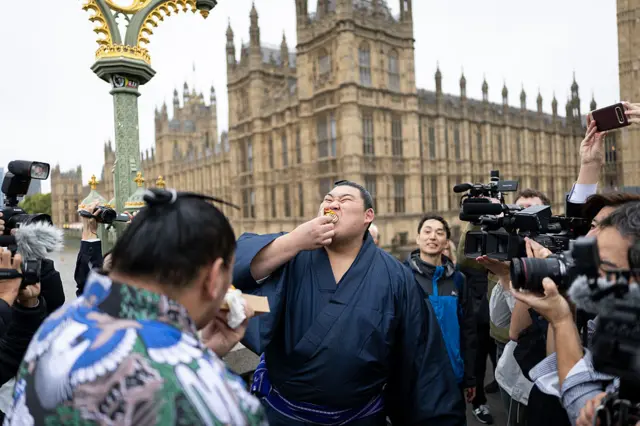 Wrestler Onosato eats a Hot Dog in front of the Houses of Parliament
