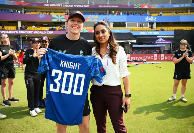 Heather Knight is presented with a 300 shirt by Isa Guha
