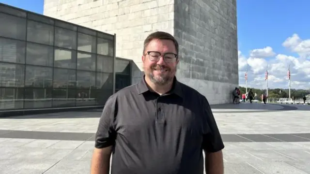 A man stands in front of the Washington Monument