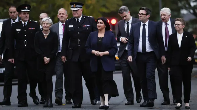 British Home Secretary Shabana Mahmood, Mayor of Greater Manchester Andy Burnham and Leader of Manchester City Council Cllr Bev Craig walk as they arrive to Crumpsall Lane to make statements. They're all wearing black, sombre clothing