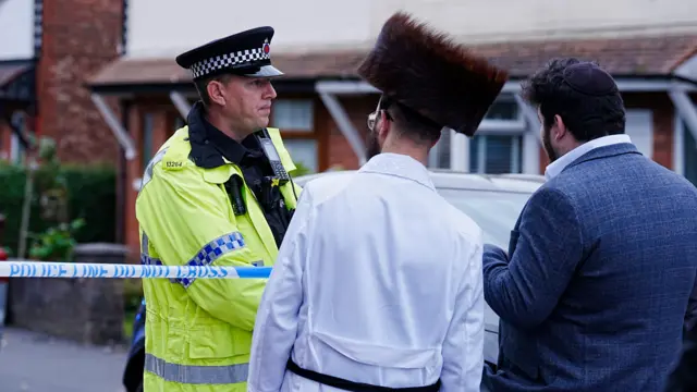 Police officer speaks to two members of the Jewish community