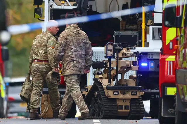 A brown robot with camouflaged officers