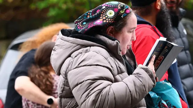 Woman reads book outside synagogue