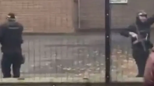 Screengrab of a video showing two armed policemen standing between a metal fence
