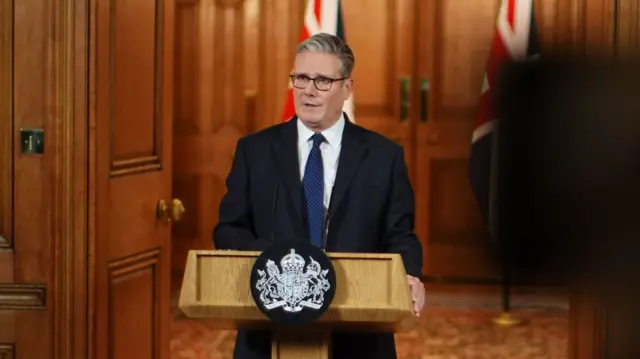 Keir Starmer speaking at podium, behind him are two UK flags