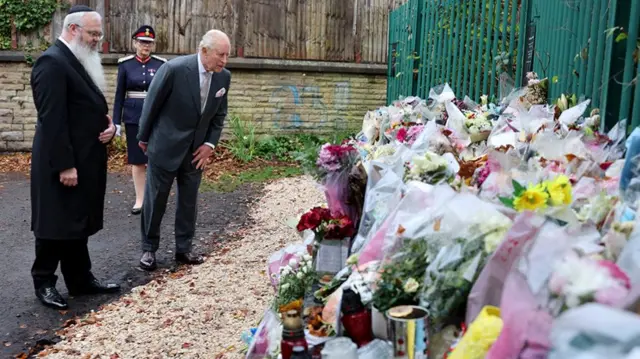 King Charles looking at flowers from well wishers