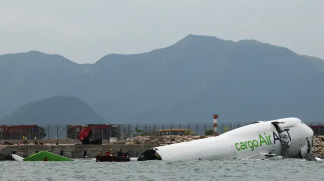A cargo plane lies partially in the sea after veering off the runway during landing at Hong Kong International Airport in Hong Kong