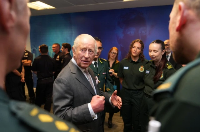 The King surrounded by ambulance staff in their green uniforms