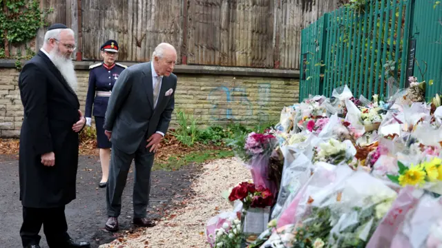 King Charles looking at floral tributes
