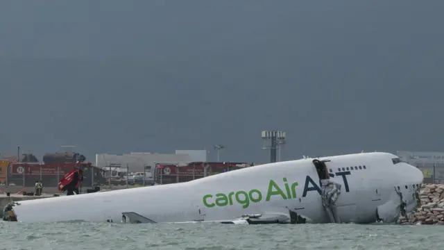 A cargo plane lies partially in the sea after veering off the runway during landing at Hong Kong International Airport in Hong Kong