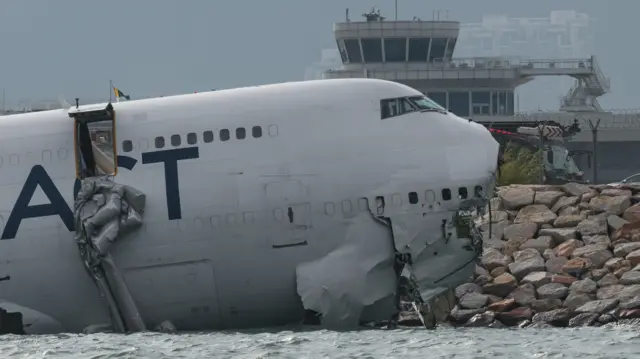A cargo plane lies partially in the sea after veering off the runway during landing at Hong Kong International Airport in Hong Kong