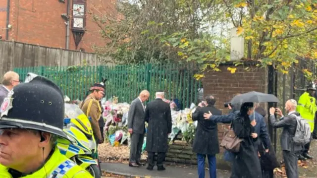 King Charles looking at flowers outside the synagogue