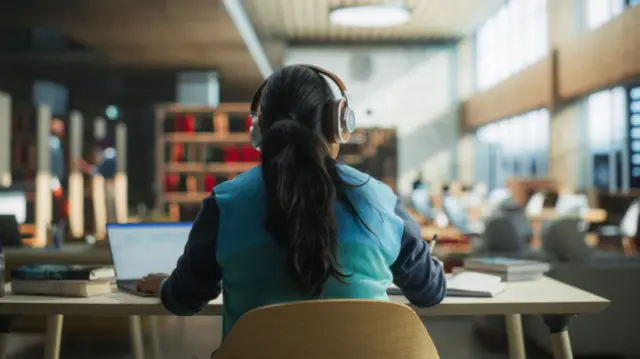 A girl wearing headphones works at a desk