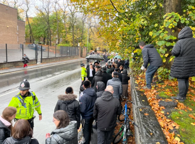 Well-wishers line street under umbrellas to see King Charles