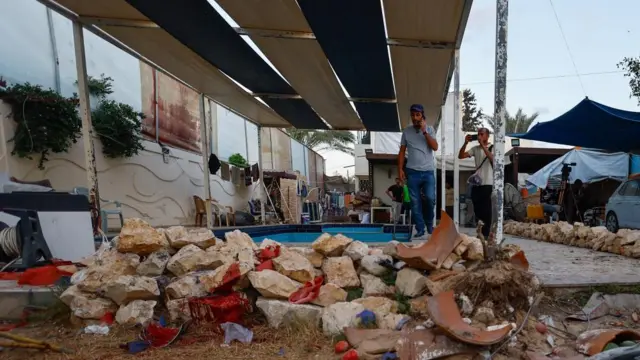 Palestinians inspect the site of an Israeli airstrike that targeted a residential compound housing employees of the Palestine Media Production Company, according to the civil defense, in Zawaida in the central Gaza Strip,